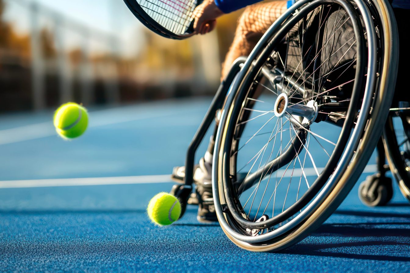 A close-up of a wheelchair tennis player hitting a ball on a blue court.